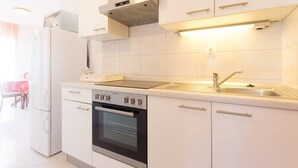 Moderni keittiö, jossa on valkoiset kaapit, sisäänrakennettu uuni, mikroaaltouuni ja ruostumattomasta teräksestä valmistettu pesuallas.