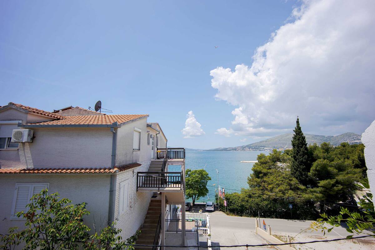 A building with a tiled roof, a balcony, and a view of the sea.