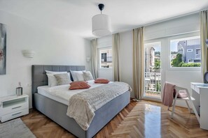 Et moderne soveværelse med en stor seng, et skrivebord og udsigt ud