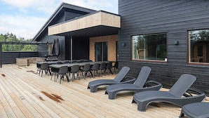 Ein modernes Haus mit Terrasse, Sitzgelegenheiten im Freien und Grillplatz.