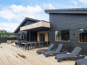 A modern house with a deck, outdoor seating, and a barbecue area. - 5 Star Holiday Home in Hojslev (Hojslev)