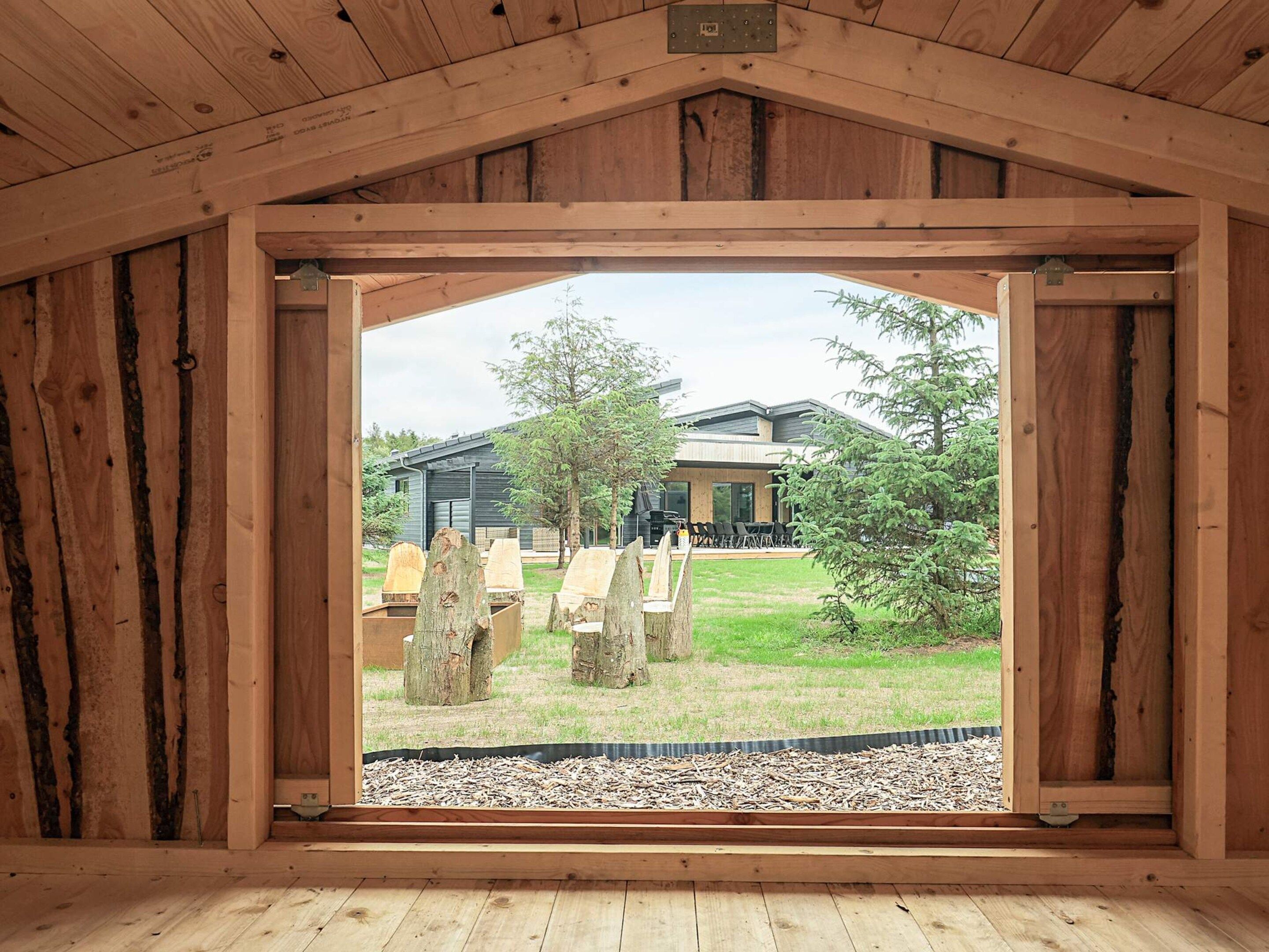 A wooden-framed room with a view of an outdoor seating area and a building in the background.
