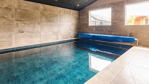 Ein Pool mit blauer Färbung, eine Steinmauer und eine Bank.