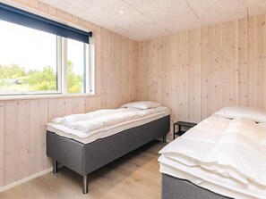 A bedroom with a single bed, a smaller bed, a window with a view of greenery, and wooden walls. - 5 Star Holiday Home in Hojslev (Hojslev)