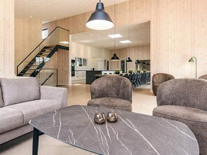 Un intérieur moderne avec un canapé, une table en marbre et un escalier menant à un espace cuisine.