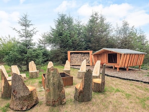 A rustic wooden structure with a sloped roof, surrounded by large tree stumps arranged in a circle. - 5 Star Holiday Home in Hojslev (Hojslev)