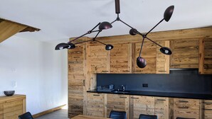 Une cuisine moderne avec des meubles en bois, un plan de travail noir et un coin repas comprenant une table en bois et des chaises noires.