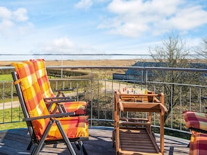 A deck with a wooden table and chairs, a view of a rural landscape, and a metal railing. - 6 Person Holiday Home in Oster Assels (Øster Assels)