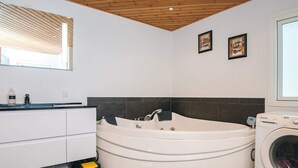 Un baño moderno con una bañera independiente, lavadora integrada y un mueble lavabo con espejo.