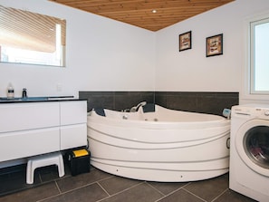 A modern bathroom with a freestanding bathtub, a built-in washing machine, and a vanity with a mirror. - 6 Person Holiday Home in Oster Assels (Øster Assels)