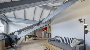 Un espacio habitable moderno estilo loft, con techo inclinado, comedor y sofá.