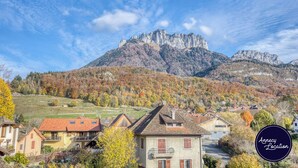 Un paisaje montañoso con un pico rocoso destacado y un pueblo con casas tradicionales.