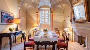 Ein Esszimmer mit einem runden Tisch, gedeckt für sechs Personen, umgeben von Holzstühlen mit roten Kissen.