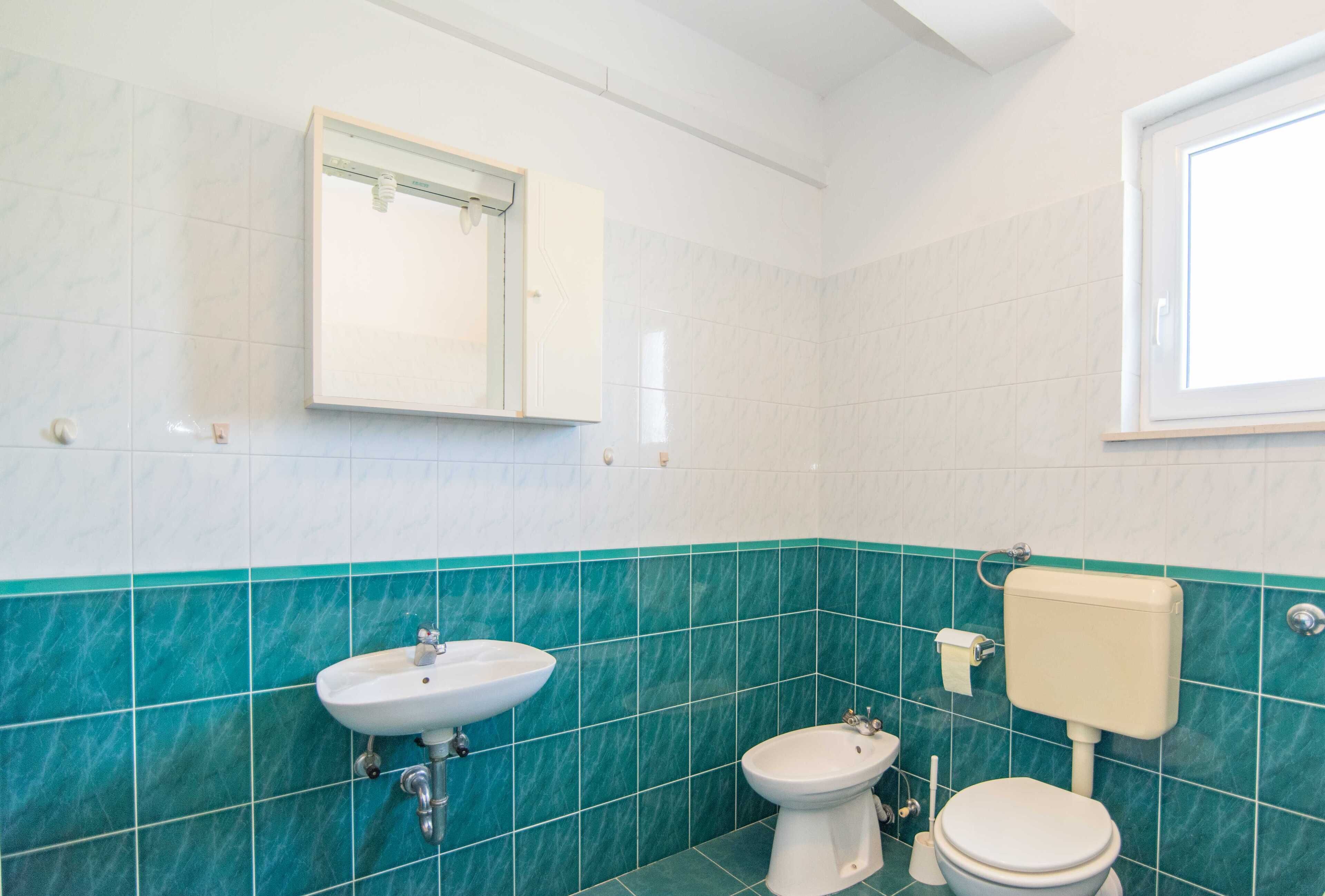A bathroom with a sink, bidet, toilet, and a mirror.