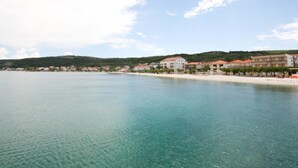 A coastal town with buildings along the shore, a sandy beach, and a calm sea. - Spacious Beachfront Apartment Ciovo (Split)