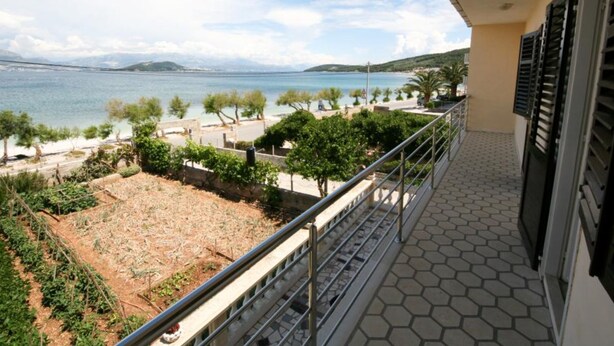 A balcony with a view of a coastal area, including a body of water and distant mountains. - Spacious Beachfront Apartment Ciovo (Split)