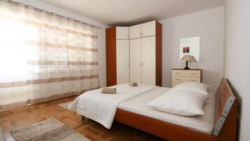 Un dormitorio con cama de madera, mesita de noche, armario y ventana con cortinas.