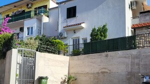 Zona residencial amb un edifici blanc, una porta verda i un patinet aparcat.