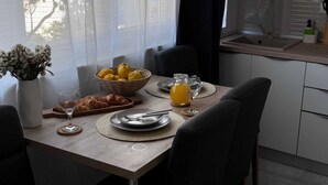 Zona de dinar amb una taula preparada per a dos, amb un ram de flors, croissants i una cistella de limones.
