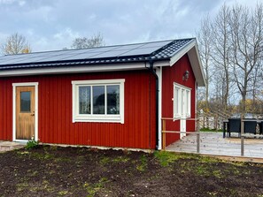 A red building with a solar panel roof, a wooden door, and a window with white frames. - 4 Star Holiday Home in Bredaryd (Bredaryd)