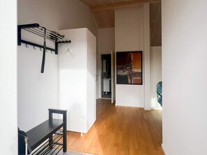 A hallway with a wooden floor, a white wall with a black metal rack, and a painting. - 4 Star Holiday Home in Bredaryd (Bredaryd)