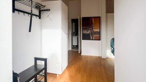 Un intérieur moderne avec un plancher en bois, une chaise noire, un meuble blanc et un tableau accroché au mur.