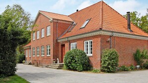 A two-story brick house with a sloped roof, a front porch, and a chimney. - 4 Star Holiday Home in Saeby (Sæby)