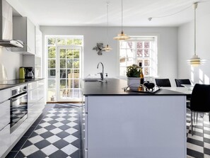 Una cocina moderna con una isla central, un comedor con sillas y un amplio ventanal que proporciona luz natural.
