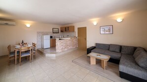 A compact living space with a dining area, kitchenette, and a sofa. - Cozy Beachfront Holiday Home Slatine (Split)