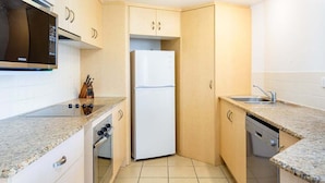 Eine kompakte Küche mit Mikrowelle, Kühlschrank, Backofen und Geschirrspüler.