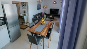 A modern kitchen with a refrigerator, dining table, and chairs. There is a sofa and a TV in the living area. - Scenic Sea View Apartment Trogir (Seget)