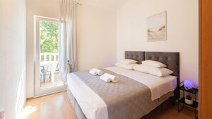 A bedroom with a bed, a nightstand, a window with curtains, and a view of the outdoors. - Spacious Prgomet Retreat With Private Pool, Fitness Centre, and Garden (Prgomet)