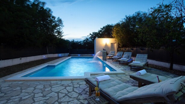 A swimming pool with lounge chairs and a stone patio. - Spacious Prgomet Retreat With Private Pool, Fitness Centre, and Garden (Prgomet)