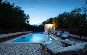 Una piscina con sillas de descanso y un patio de piedra.