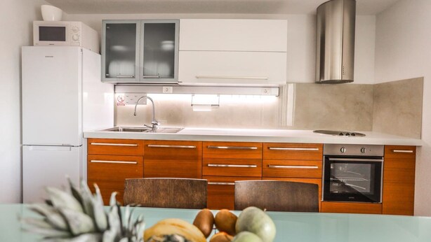 A modern kitchen with white cabinets, a stainless steel range hood, a built-in oven, and a microwave on the countertop. - Secluded Holiday Home With Pool and Hot Tub (Lecevica)