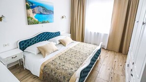 A bedroom with a bed, a nightstand, a wardrobe, and a painting of a coastal landscape.
