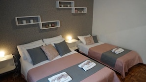 A hotel room with two beds, each with a bedside table and lamp. There are wall-mounted shelves above the beds. - Modern Trogir Apartment With Private Patio, Bbq, and Close to Beach (Trogir)