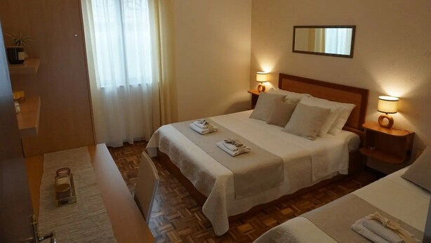 Ein Hotelzimmer mit einem großen Bett, zwei Nachttischen mit Lampen, einem Holzboden und einem Spiegel an der Wand.