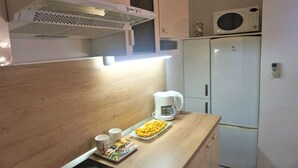 A kitchen with a microwave, coffee maker, and a plate of food on the counter. - Modern Trogir Apartment With Private Patio, Bbq, and Close to Beach (Trogir)