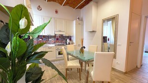 A modern kitchen with white cabinets, a tiled backsplash, and a dining area with a glass table and white chairs.