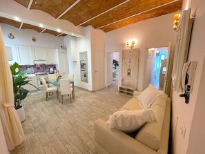 A spacious living area with a white sofa, a dining table with chairs, and a kitchen in the background. - My Luxury M&G Florence (Firenze)