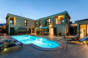 Relax by the pool surrounded by lounge chairs and a table, with large windows and balconies offering outdoor space.