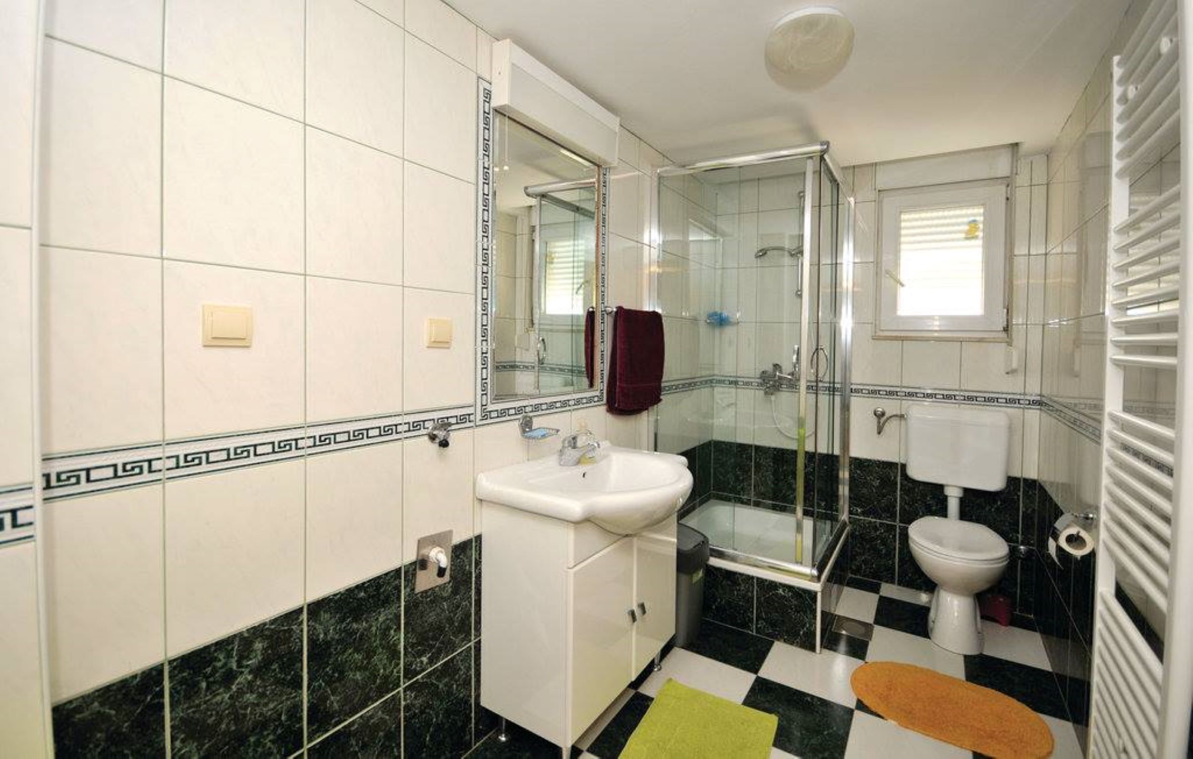 A bathroom with a glass shower enclosure, a white sink, and a toilet.
