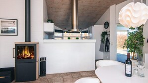A modern kitchen with a wood-burning stove, white cabinetry, and a hanging light fixture. - 4 Star Holiday Home in Ronde (Ronde)