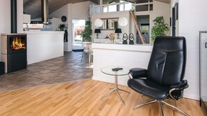 A modern kitchen with a central island, a fireplace, and a dining area with a black leather chair. - 4 Star Holiday Home in Ronde (Ronde)