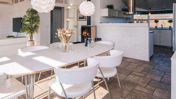 A modern kitchen with white cabinetry, a central island, and hanging pendant lights. - 4 Star Holiday Home in Ronde (Ronde)