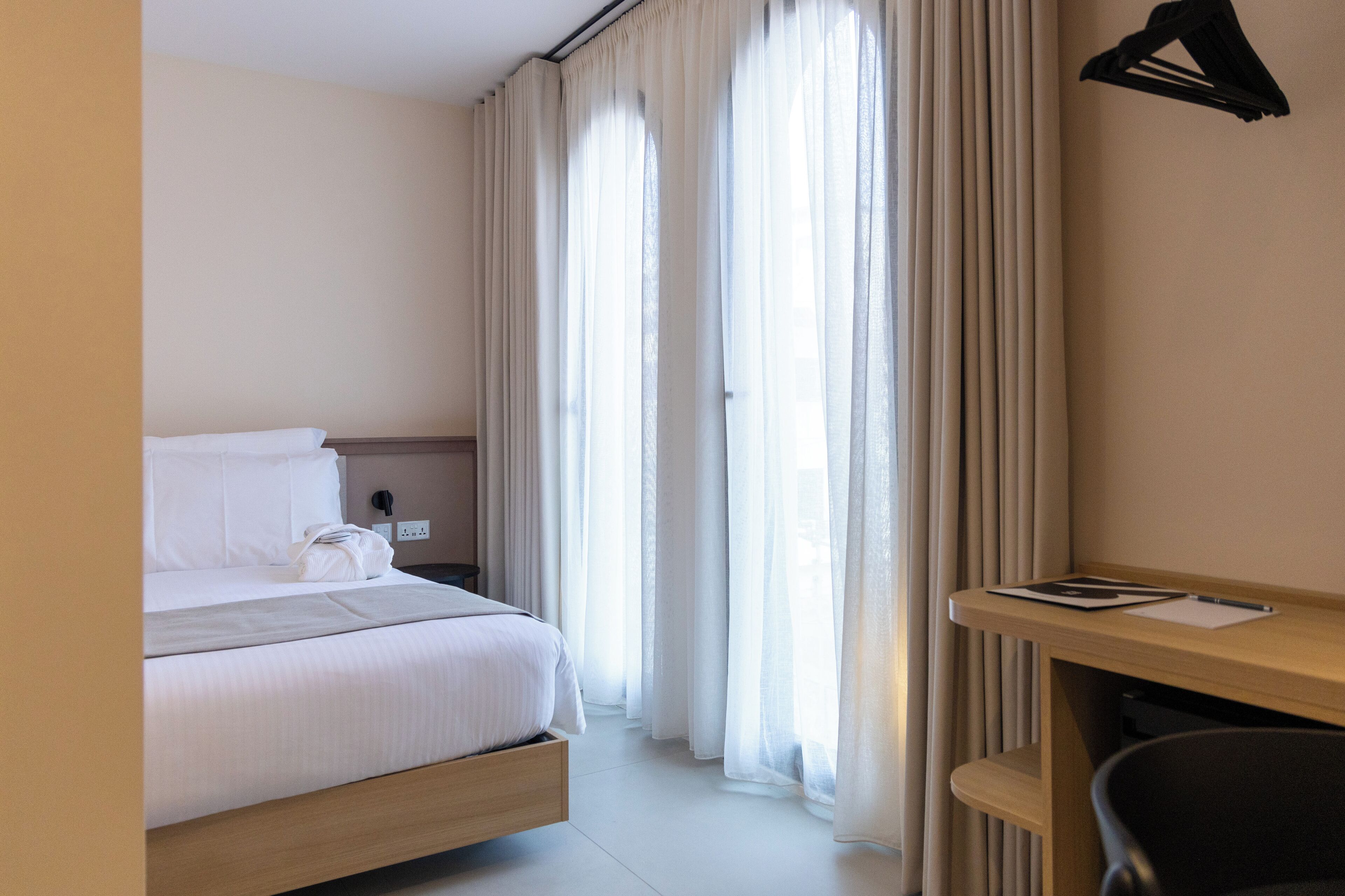Een hotelkamer met een bed, een bureau en een stoel.