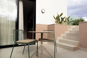 Un espace extérieur moderne, aménagé avec deux chaises et une table, un escalier et un pot de fleurs.