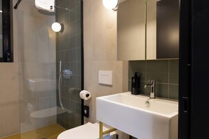 Un baño moderno con ducha de vidrio, un lavabo blanco y un espejo sobre el lavabo.