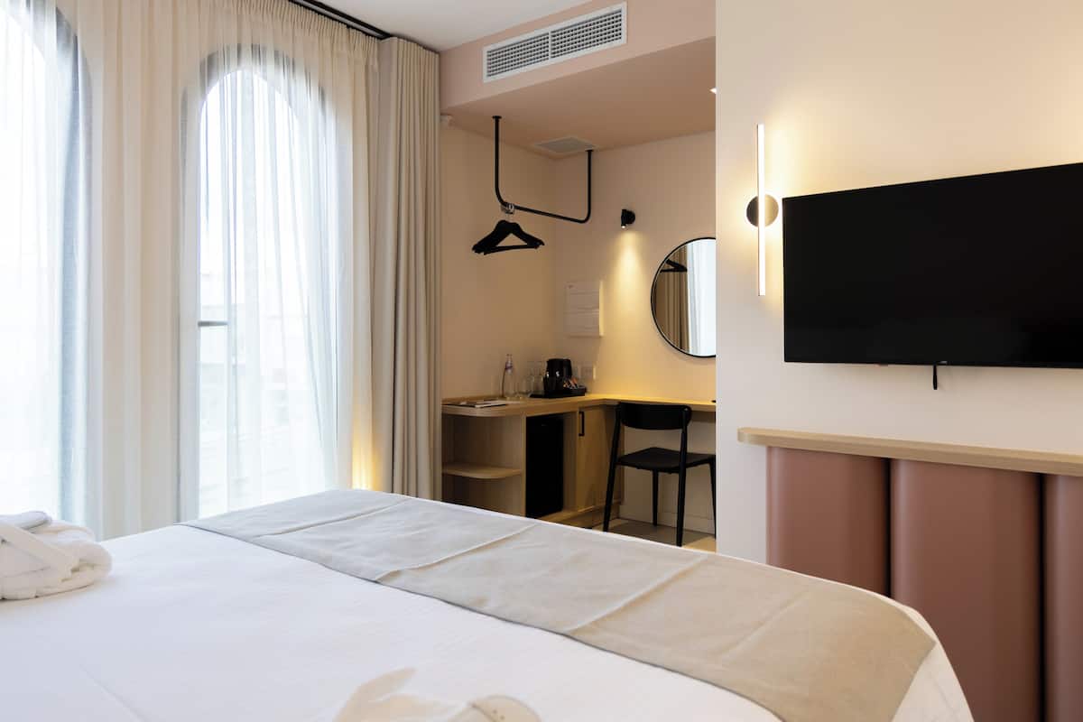 Ein Hotelzimmer mit Bett, Schreibtisch, Stuhl, Fernseher und einem Badezimmer mit Duschvorhang.